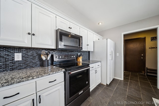 kitchen with stainless steel microwave, dark stone countertops, range with electric stovetop, and white cabinetry