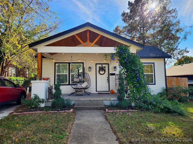 bungalow-style house with covered porch, fence, and a front lawn