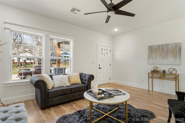 living area with visible vents, a wealth of natural light, and wood finished floors