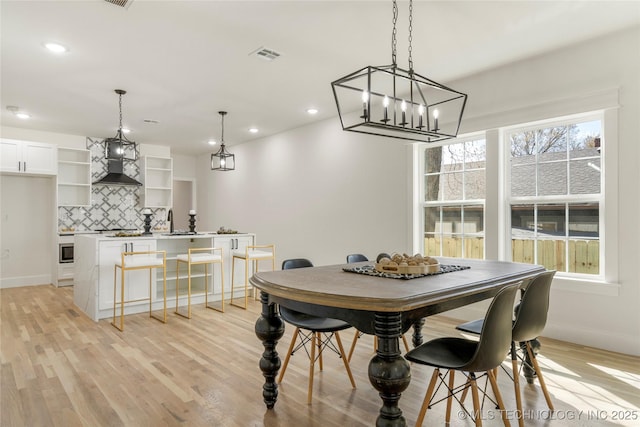 dining space with baseboards, light wood-type flooring, visible vents, and a healthy amount of sunlight