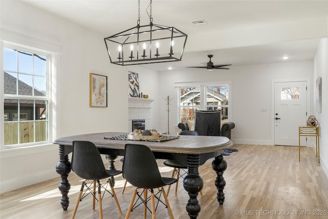 dining space with ceiling fan, recessed lighting, a fireplace, baseboards, and light wood-type flooring