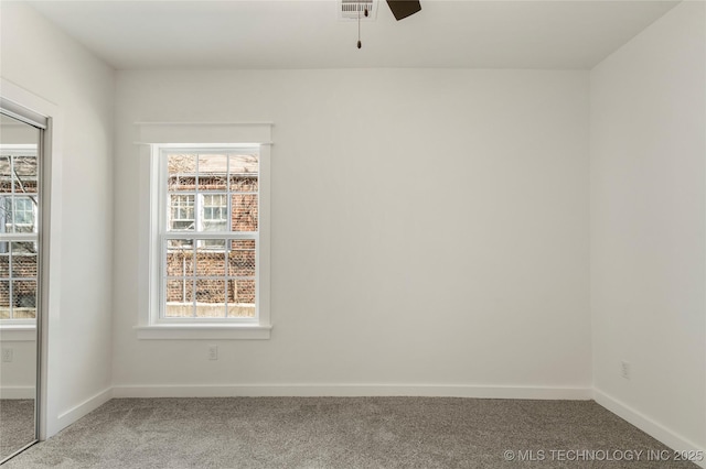 spare room with carpet floors, a healthy amount of sunlight, baseboards, and visible vents