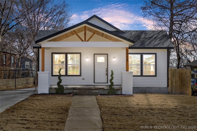 bungalow-style house featuring fence, a front lawn, and roof with shingles