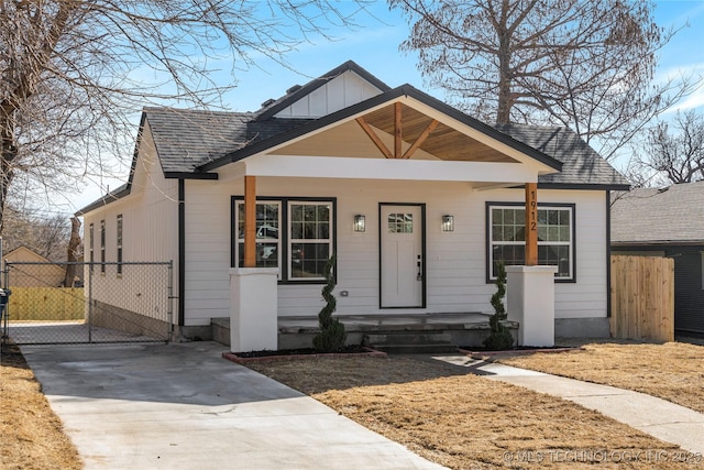 bungalow-style house featuring a shingled roof, fence, and board and batten siding