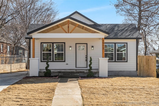 bungalow with a shingled roof and fence