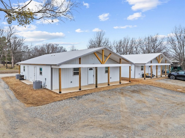 modern farmhouse style home featuring metal roof, central AC, and driveway