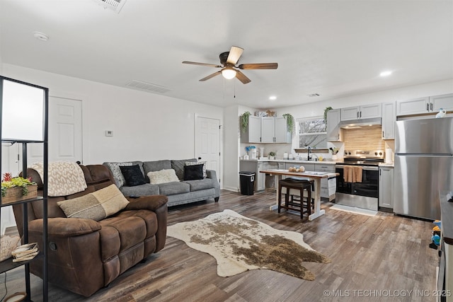 living room with dark wood-style floors, recessed lighting, visible vents, and ceiling fan