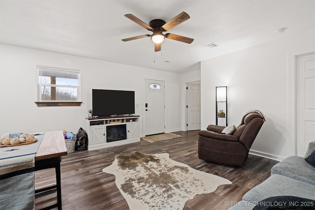 living room featuring a ceiling fan, baseboards, visible vents, and dark wood-type flooring