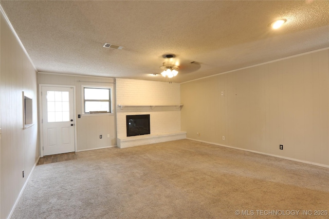 unfurnished living room with ceiling fan, ornamental molding, a textured ceiling, carpet flooring, and a brick fireplace