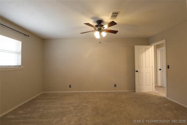 unfurnished room featuring light colored carpet, visible vents, ceiling fan, and a textured ceiling