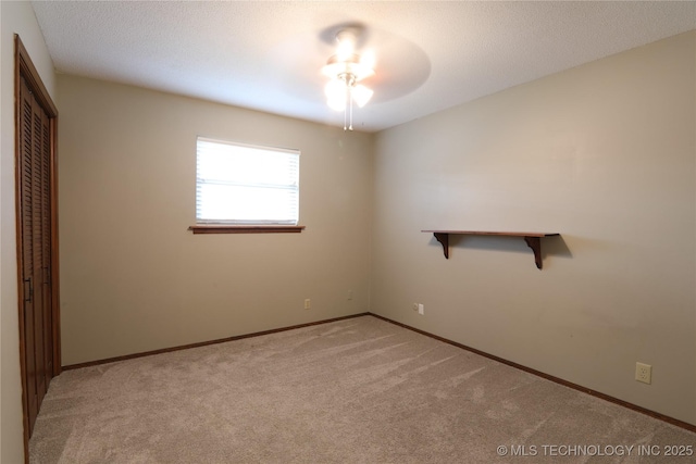 unfurnished room with a ceiling fan, baseboards, a textured ceiling, and light colored carpet