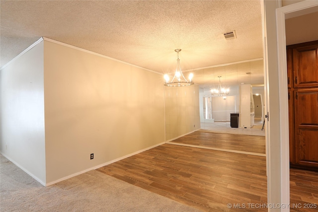 unfurnished dining area featuring visible vents, ornamental molding, wood finished floors, a textured ceiling, and a chandelier