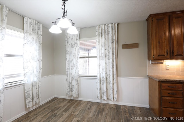 unfurnished dining area with dark wood-style floors and wainscoting