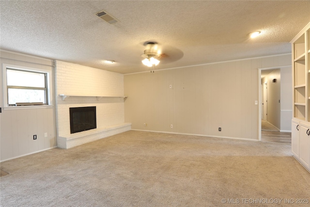 unfurnished living room featuring light carpet, visible vents, ornamental molding, a textured ceiling, and a brick fireplace