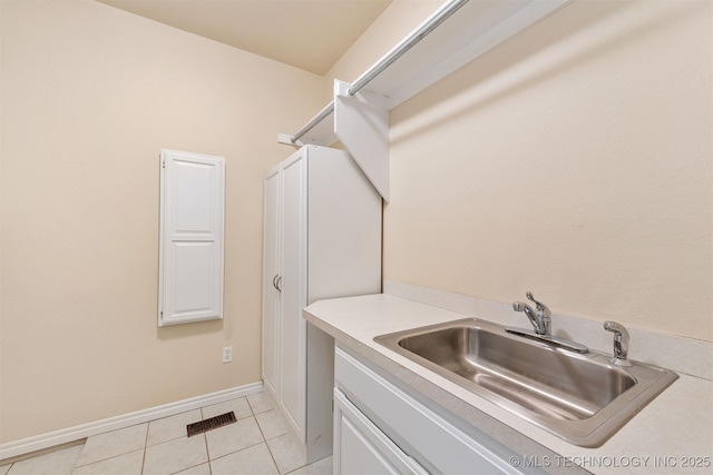 laundry room featuring light tile patterned floors, a sink, visible vents, and baseboards