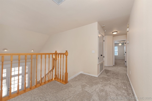 corridor featuring baseboards, light carpet, visible vents, and an upstairs landing