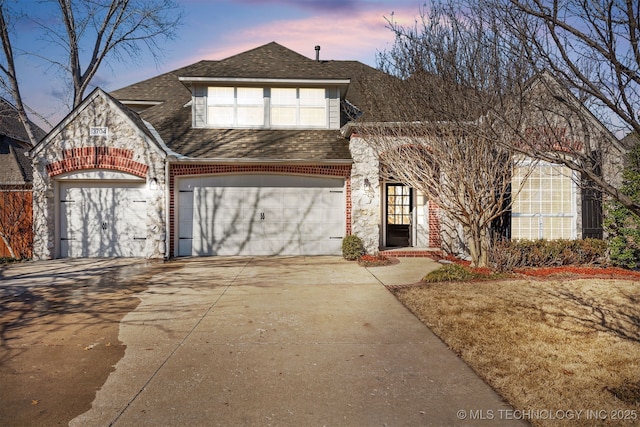 view of front of house featuring a garage, driveway, brick siding, and a shingled roof