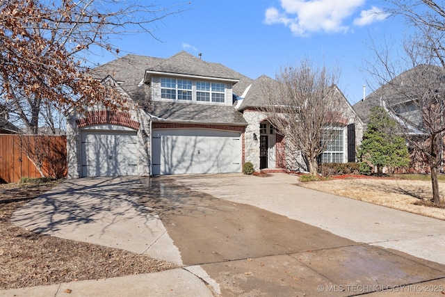 view of front facade with a garage, stone siding, driveway, and fence