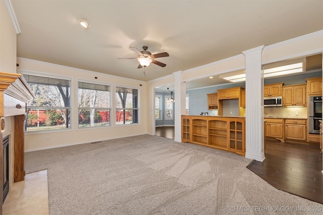 unfurnished living room featuring crown molding, a fireplace with flush hearth, and ornate columns