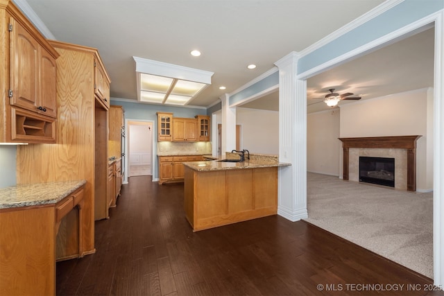 kitchen featuring glass insert cabinets, open floor plan, a peninsula, and light stone counters