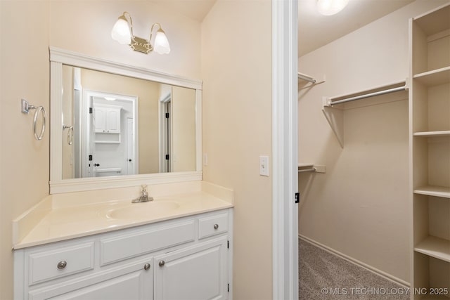 bathroom with a walk in closet and vanity