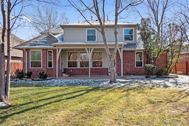 traditional home featuring brick siding, fence, and a front lawn