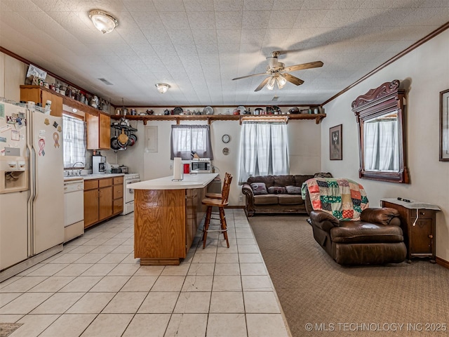 kitchen featuring white appliances, a kitchen island, brown cabinets, open floor plan, and light countertops