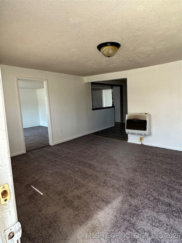 spare room with a textured ceiling, dark colored carpet, and heating unit