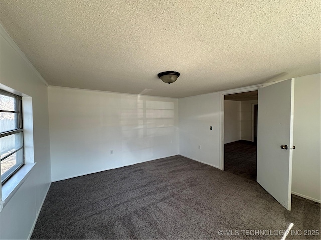 unfurnished room with a textured ceiling and dark colored carpet