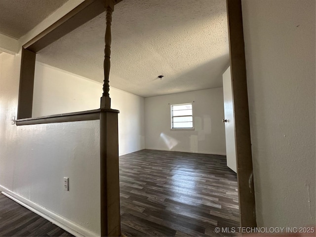 interior space featuring vaulted ceiling, dark wood finished floors, and a textured ceiling