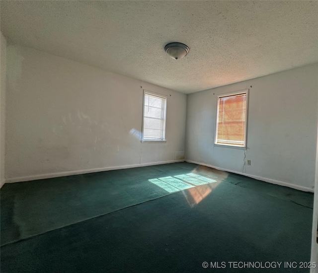 spare room with a textured ceiling, carpet floors, and baseboards