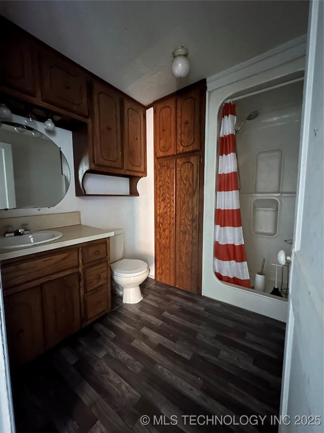 bathroom featuring curtained shower, vanity, toilet, and wood finished floors