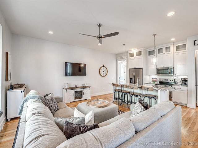 living room with baseboards, recessed lighting, a ceiling fan, and light wood-style floors