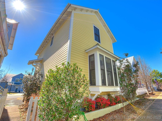 view of property exterior with fence and a sunroom