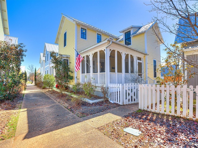 view of front of property with a fenced front yard and a sunroom