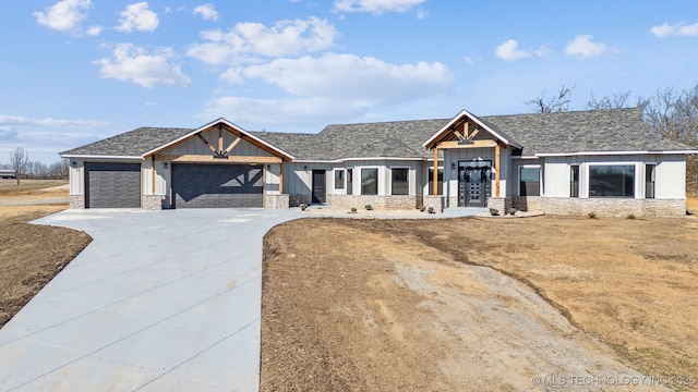 view of front of house with roof with shingles, concrete driveway, board and batten siding, a garage, and stone siding