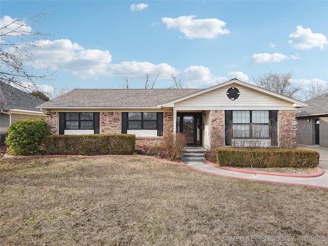 single story home with brick siding, a shingled roof, and a front yard