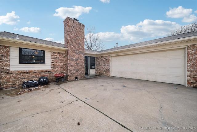 exterior space with brick siding, driveway, a chimney, and an attached garage