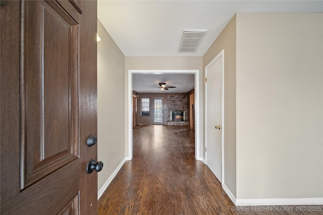 hallway featuring dark wood finished floors, visible vents, and baseboards