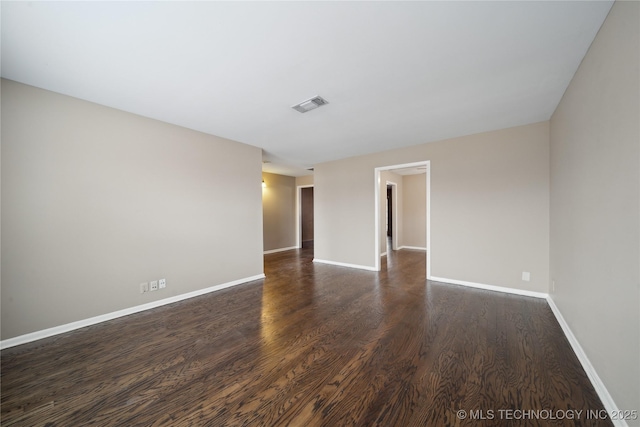 unfurnished room with baseboards, visible vents, and dark wood finished floors