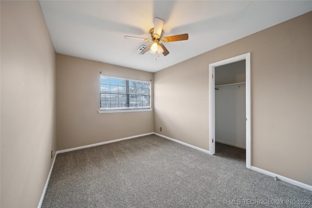 unfurnished bedroom with visible vents, baseboards, ceiling fan, a walk in closet, and carpet floors