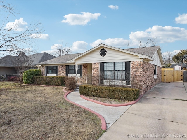 ranch-style house with roof with shingles, a front yard, fence, and brick siding