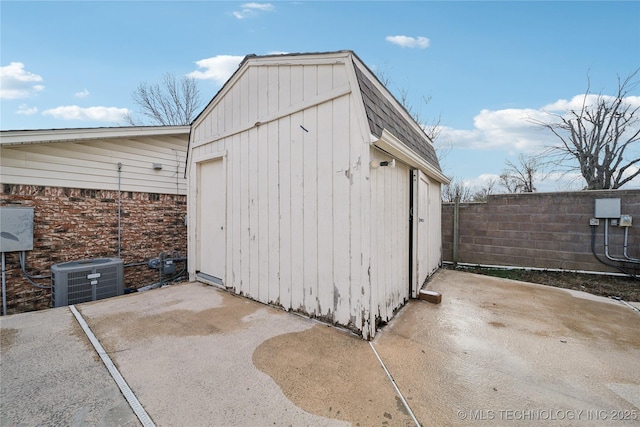 view of outdoor structure featuring central air condition unit, fence, and an outbuilding