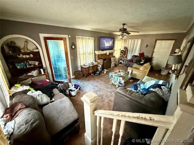 living area featuring ceiling fan, a fireplace, ornamental molding, and a textured ceiling