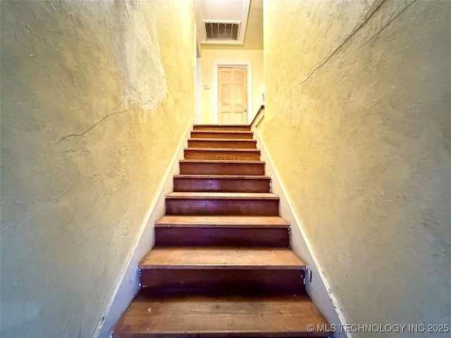 staircase featuring visible vents and a textured wall