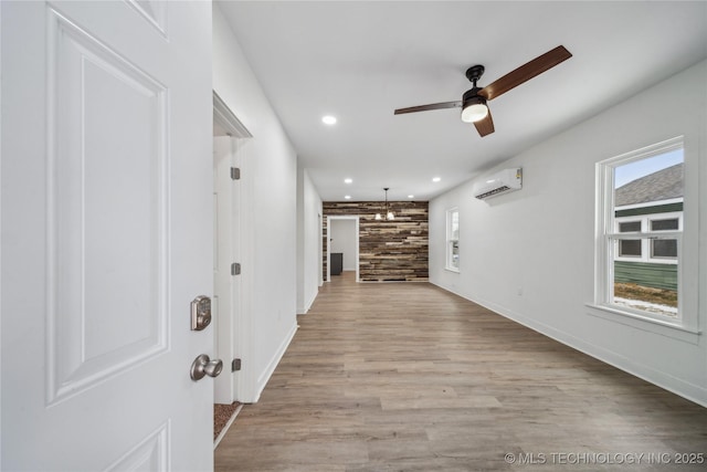 hall featuring a wall unit AC, light wood-style floors, baseboards, and recessed lighting