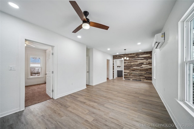 unfurnished living room with recessed lighting, light wood-style flooring, an accent wall, a ceiling fan, and a wall mounted air conditioner