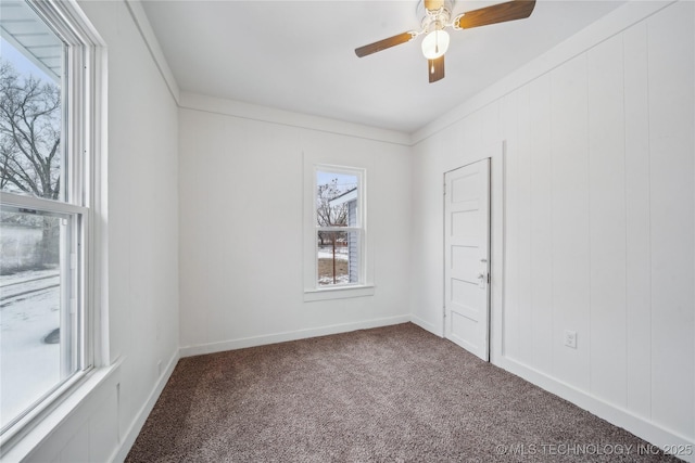 unfurnished room with ceiling fan, dark carpet, and baseboards