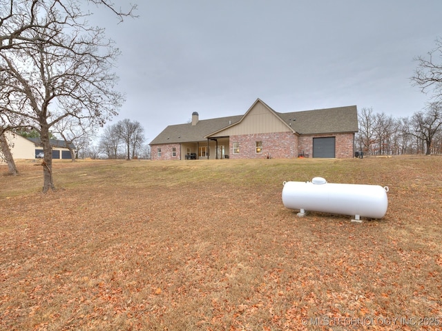 exterior space with brick siding, an attached garage, a chimney, and a front lawn