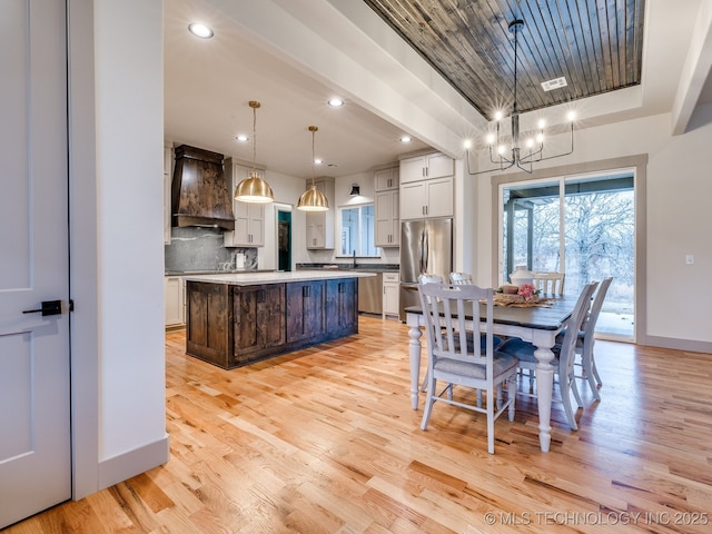 dining space with recessed lighting, a raised ceiling, light wood-style flooring, an inviting chandelier, and baseboards